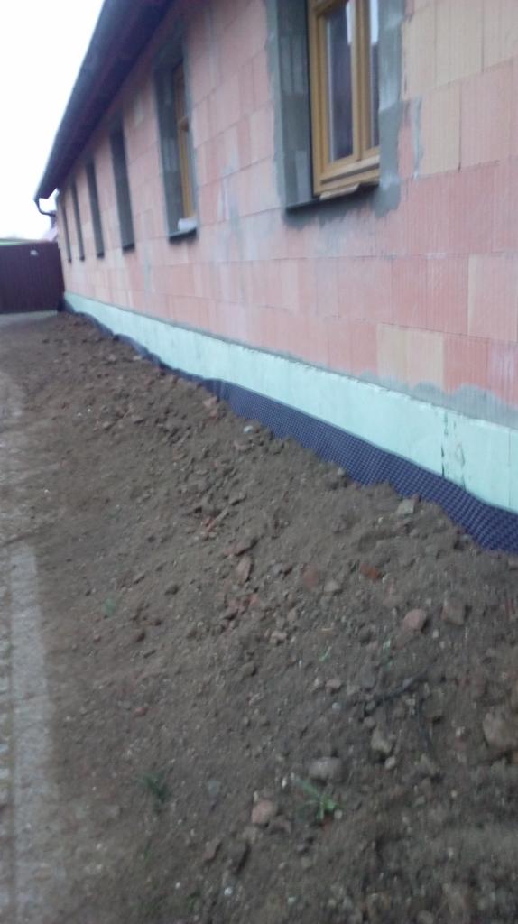 Fundament domu murowanego z widoczną izolacją przeciwwilgociową i termiczną, zasypywany ziemią.
