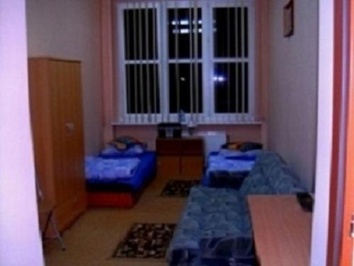 Pokój z trzema łóżkami, szafą i oknem z żaluzjami, widok z perspektywy wejścia.