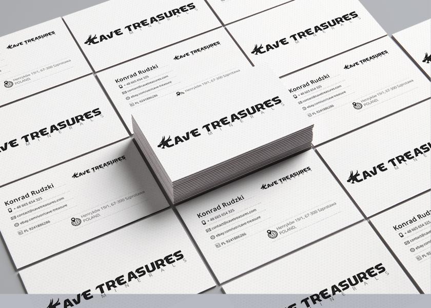 Stos wizytówek firmowych z czarnym logo i danymi kontaktowymi na białym tle, ułożonych pod kątem.