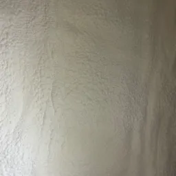 Szczegółowa tekstura szarej pianki izolacyjnej PUR, widoczne nierówności i porowata powierzchnia, charakterystyczna dla natryskowej izolacji termicznej.