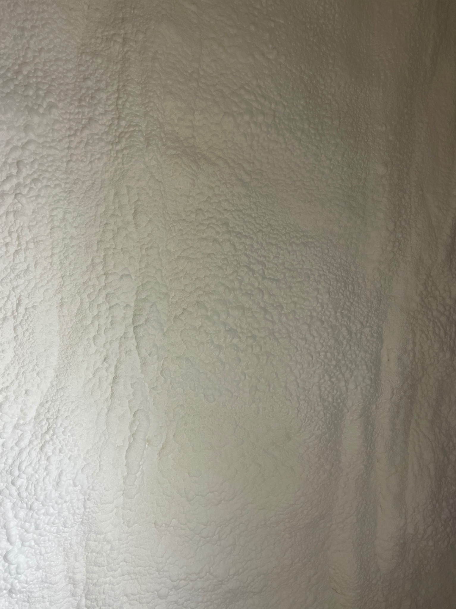 Szczegółowa tekstura szarej pianki izolacyjnej PUR, widoczne nierówności i porowata powierzchnia, charakterystyczna dla natryskowej izolacji termicznej.