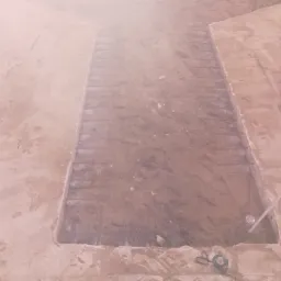 Przygotowanie podłoża: wykop z ułożonym zbrojeniem pod wylewkę. Widoczne narzędzia pomiarowe i poziomica. Surowe wykończenie, etap prac budowlanych.