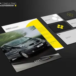 Zestaw materiałów firmowych z logo i hasłem 'Wynajem Długoterminowy', zawierający ulotkę z dynamicznym zdjęciem samochodu, wizytówki w odcieniach szarości i czerni z geometrycznymi wzorami.