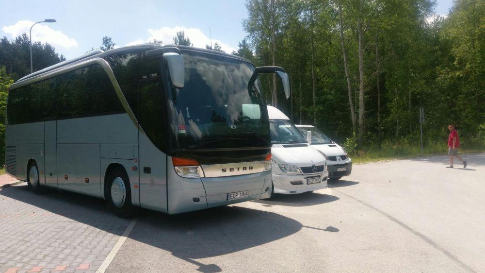 Autokar marki Setra z otwartymi drzwiami na parkingu w Opocznie, obok zaparkowane busy, w tle las.