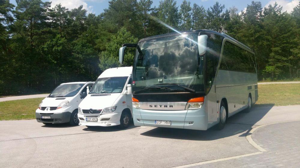Autokar Setra, bus Mercedes-Benz i Renault Trafic zaparkowane na tle lasu w słoneczny dzień.