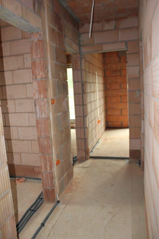 Wnętrze w trakcie budowy w Częstochowie: widoczne kable elektryczne ułożone wzdłuż ścian z cegły, przygotowane do rozprowadzenia instalacji.