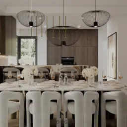 Elegancka jadalnia z marmurowym stołem, białymi krzesłami i designerskimi lampami wiszącymi. Widok na otwartą kuchnię z drewnianymi szafkami i zielenią za oknem.