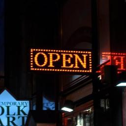 HIPERNET Sp. z o.o. - Pomarańczowy wyświetlacz LED z napisem 'OPEN' na tle nocnego miasta z innymi neonami i szyldami.