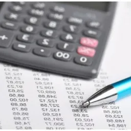 Kalkulator i niebieski długopis na wydruku z kolumnami liczb, prawdopodobnie zestawienie finansowe.