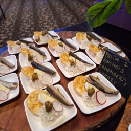Global Chefs Mariusz Powierża - Taca z przystawkami: pasta z anchois, camembert, kapary, rzodkiewka, wafle. Eleganckie dania na białych talerzykach, rustykalna drewniana taca.