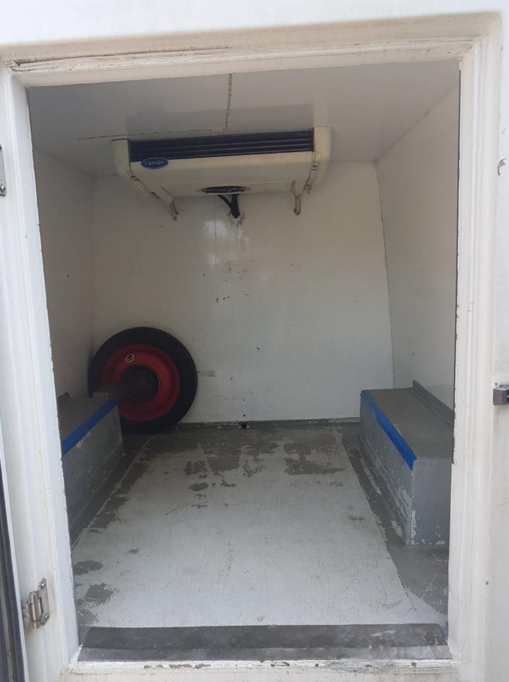 Wnętrze chłodni samochodowej z agregatem Carrier, widoczne nadkole i opona zapasowa.