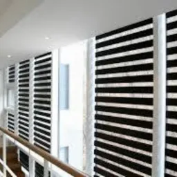 Nowoczesne okna przesłonięte czarno-białymi osłonami okiennymi typu dzień i noc, widok z korytarza, jasne wnętrze.