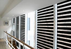 Nowoczesne okna przesłonięte czarno-białymi osłonami okiennymi typu dzień i noc, widok z korytarza, jasne wnętrze.