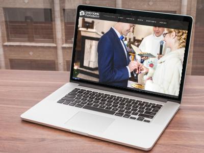 Laptop wyświetla zdjęcie ślubne pary podczas ceremonii zakładania obrączek, z logo 'Emotions Photography' w lewym górnym rogu ekranu, umieszczony na drewnianym biurku.