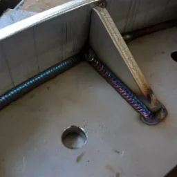 Metalowa konstrukcja spawana z widocznymi spoinami o charakterystycznym zabarwieniu, otwory w płycie podstawy.