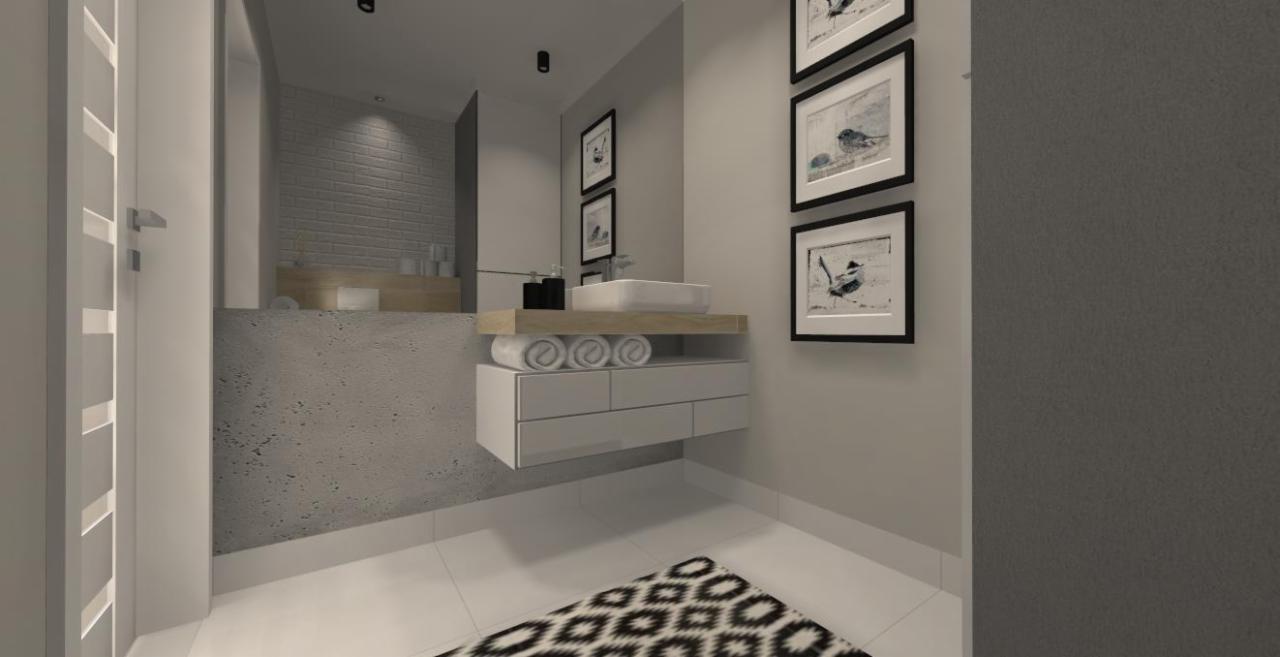 Wizualizacja nowoczesnej łazienki w odcieniach szarości i bieli z wiszącą szafką pod umywalką, trzema ręcznikami, trzema obrazkami w czarnych ramkach i wzorzystym dywanikiem.