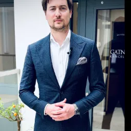 Adwokat Gabriel Gatner w Katowicach, w granatowym garniturze, prezentuje się profesjonalnie na tle drzwi z nazwą kancelarii.