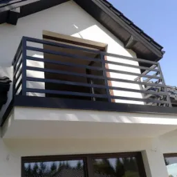 Czarna, nowoczesna barierka balkonowa z poziomych profili na tle białej elewacji domu z ciemnym dachem.