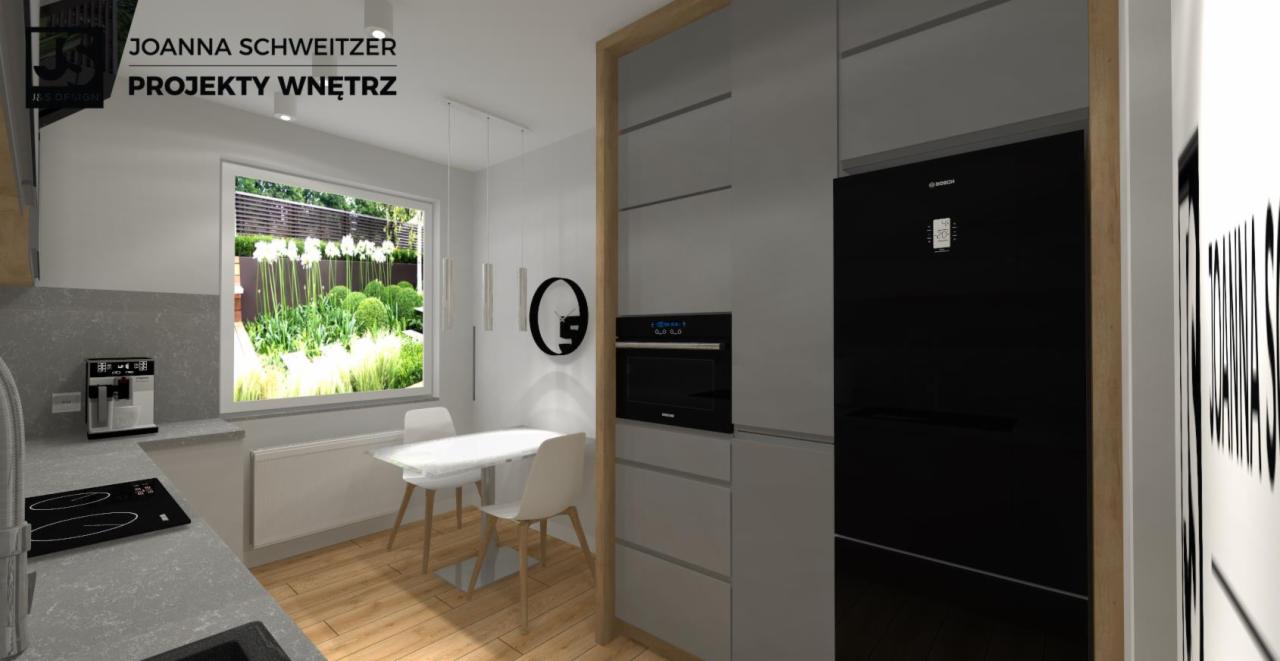 Wizualizacja kuchni z jadalnią w odcieniach szarości i bieli, z widokiem na ogród przez okno, ekspres do kawy na blacie i minimalistyczna lampa wisząca nad stołem.