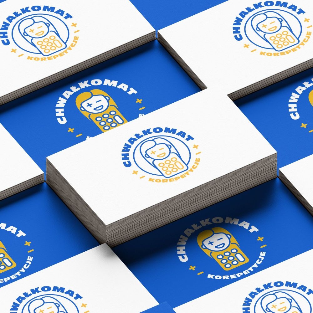 Stos wizytówek z niebiesko-żółtym logo 'ChwałkoMat' na niebieskim tle. Logo przedstawia uśmiechniętą postać w obrysie telefonu. Perspektywa z góry pod kątem.