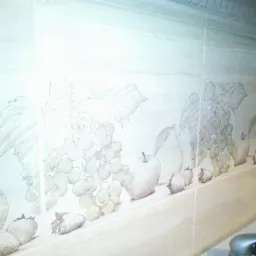 Ceramiczne płytki ścienne z motywem owoców (winogrona, gruszki, jabłka, truskawki) w kuchni w Inowrocławiu, ułożone w rzędzie wzdłuż blatu.