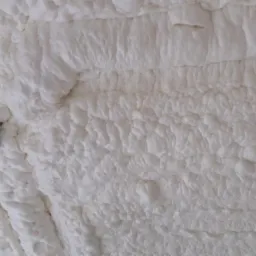 Świeżo nałożona, biała pianka PUR z widocznym fragmentem blachy w Starogardzie Gdańskim, ukazująca strukturę izolacji.