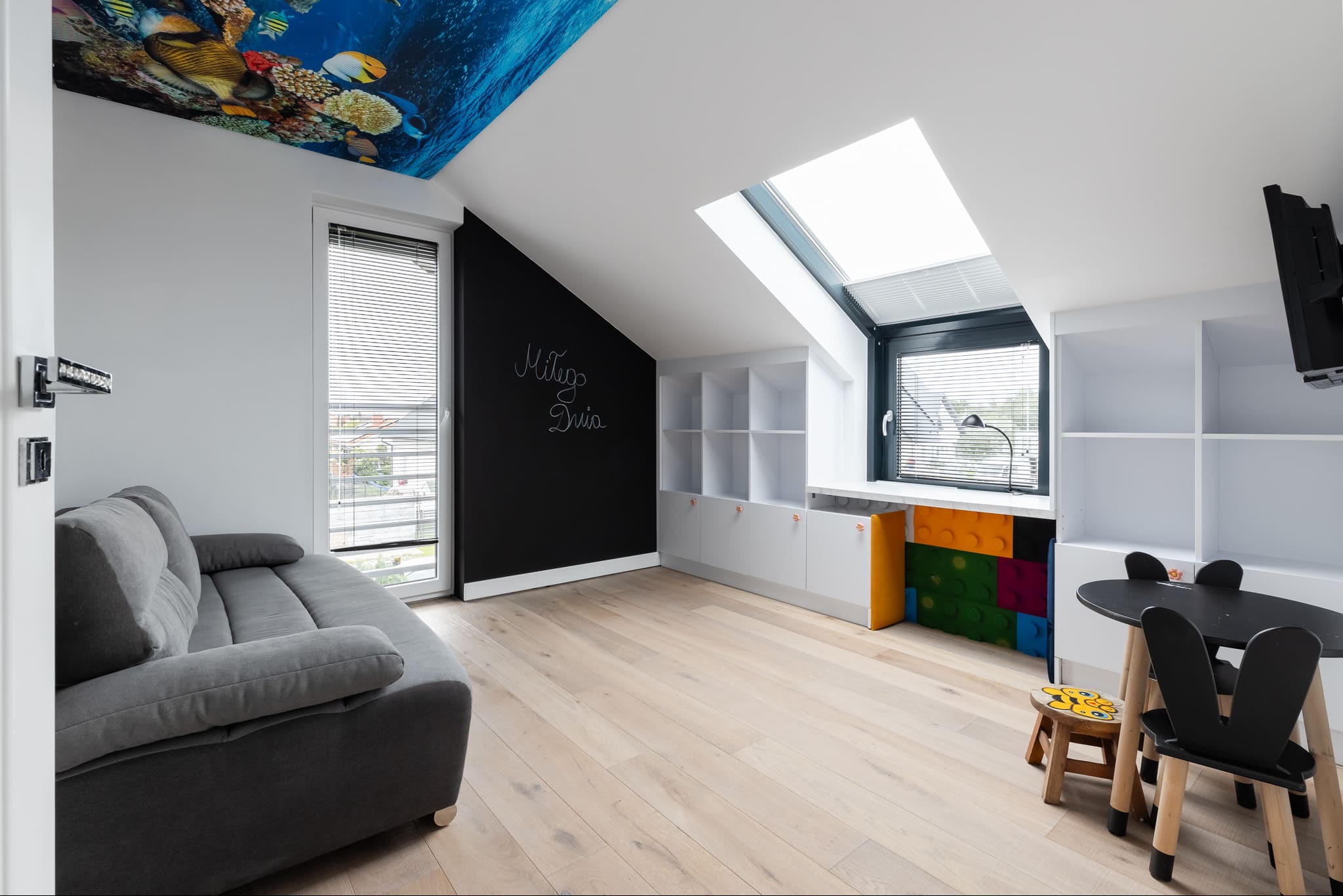 Pokój dziecięcy na poddaszu w Gdańsku: sufit napinany z motywem morskim, tablica kredowa i jasna podłoga. Nowoczesne meble i okno dachowe.