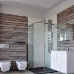 Nowoczesna łazienka z kabiną prysznicową ze szkła, umywalką z szafką, toaletą i bidetem w minimalistycznym stylu, wykończona panelami imitującymi drewno.