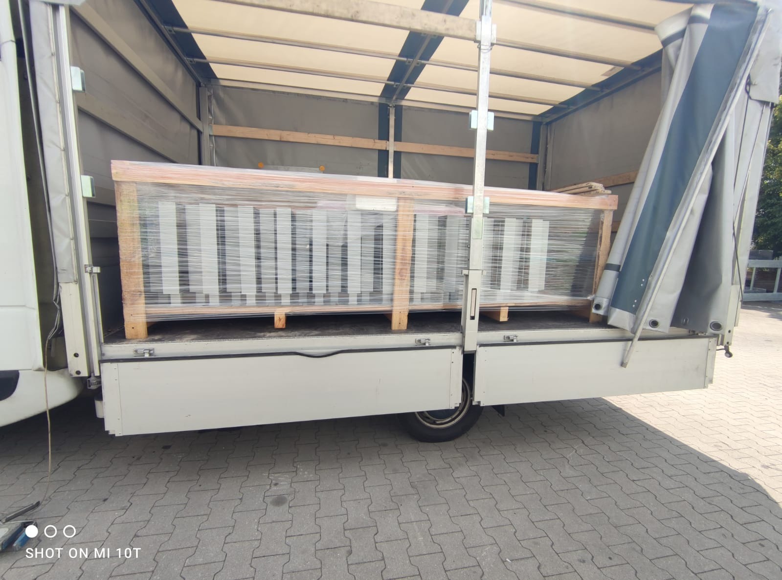 Ładunek zapakowany w folię stretch i umieszczony na paletach wewnątrz skrzyni ładunkowej samochodu dostawczego z otwartą plandeką.