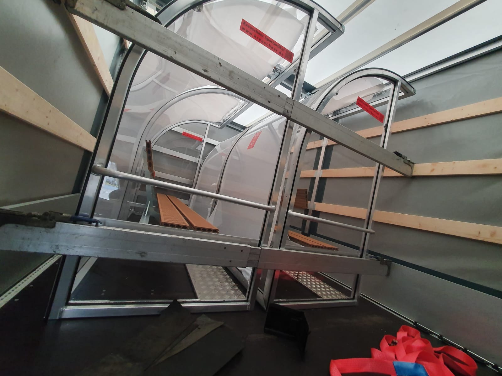 Wnętrze naczepy z zabezpieczonymi elementami konstrukcyjnymi, prawdopodobnie przystosowanymi do przewozu specyficznych ładunków, widoczne drewniane elementy mocujące i metalowe stelaże.