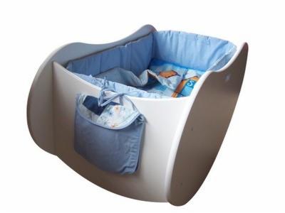 Biała, kołyskowa szafka dziecięca z niebieskim wykończeniem i kieszenią boczną, wypełniona pościelą z motywem postaci z bajek.