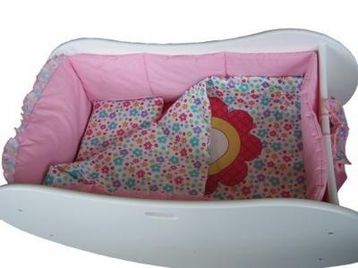 Biała, drewniana kołyska dla niemowląt z różowym wyściełanym wnętrzem i pościelą w kolorowe kwiatki.