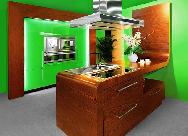 Nowoczesna kuchnia z zielonymi szafkami i drewnianą wyspą z wbudowaną płytą grzewczą i zlewem, podświetlona od góry