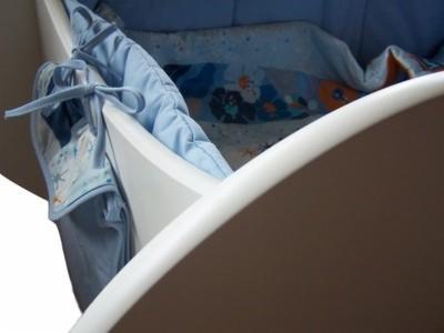 Wnętrze szafy na wymiar z jasnymi, błękitnymi tekstyliami z motywem morskim, widok z góry na półkę i boczne kieszenie.