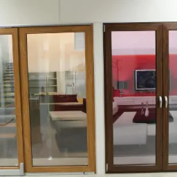 Dwa zestawy drzwi przesuwnych z drewnianymi ramami; jeden zestaw z jasnego drewna, drugi z ciemnego, z widokiem na wnętrza nowoczesnych salonów.