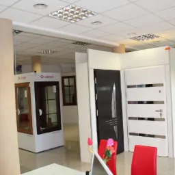 Ekspozycja różnorodnych modeli drzwi wewnętrznych i zewnętrznych w salonie w Kaliszu, widoczne drzwi drewniane i w kolorze białym z przeszkleniami.