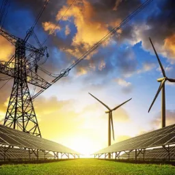 Instalacja fotowoltaiczna z turbinami wiatrowymi i słupem wysokiego napięcia na tle zachodzącego słońca i chmur.