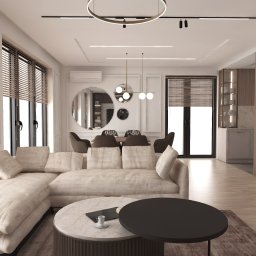 AZArchitekci Pracownia Architektury Wnętrz - Jasny salon z narożną sofą, okrągłymi stolikami kawowymi, żaluzjami w oknach i okrągłym lustrem na ścianie nad stołem jadalnym.