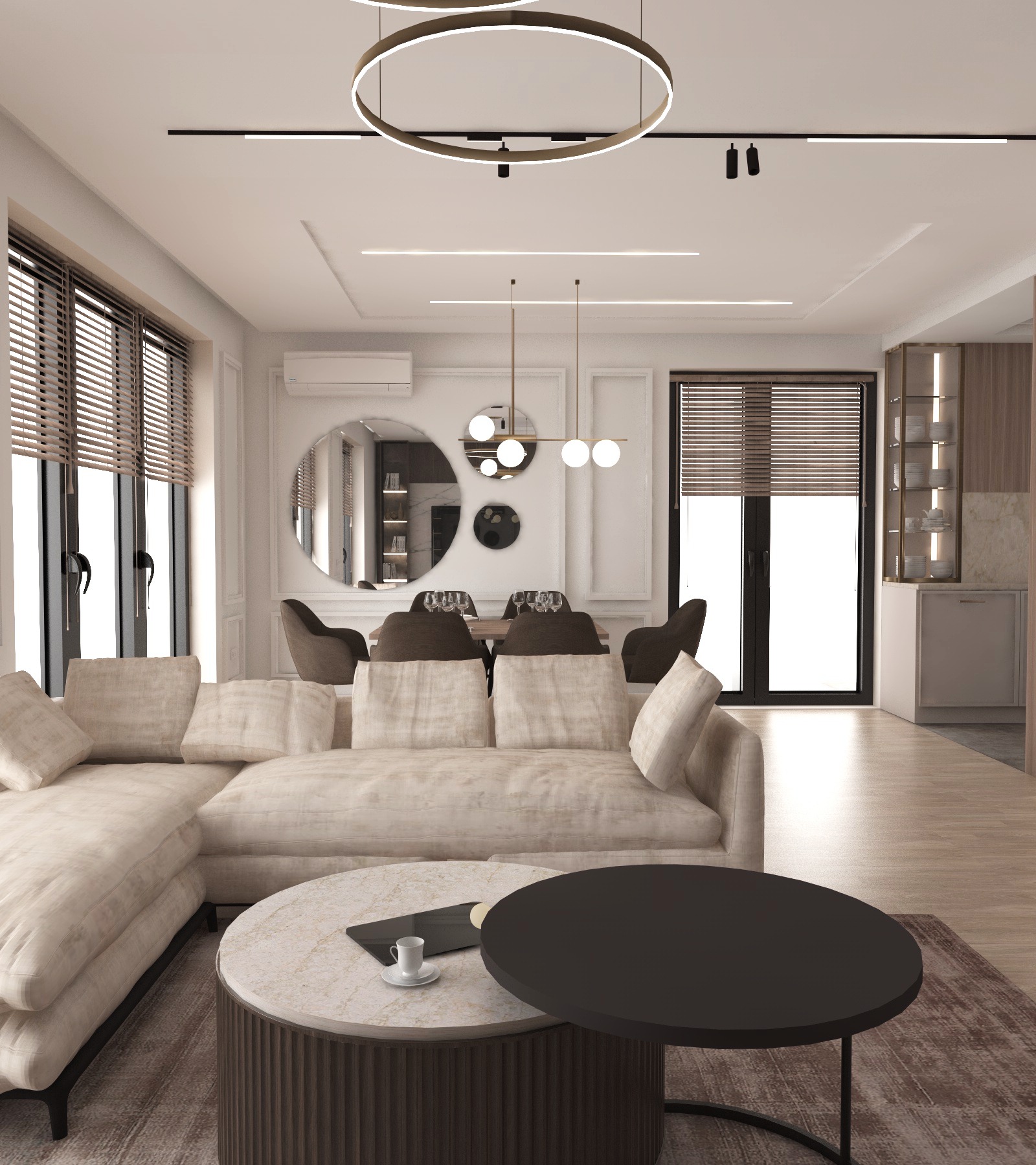 Jasny salon z narożną sofą, okrągłymi stolikami kawowymi, żaluzjami w oknach i okrągłym lustrem na ścianie nad stołem jadalnym.