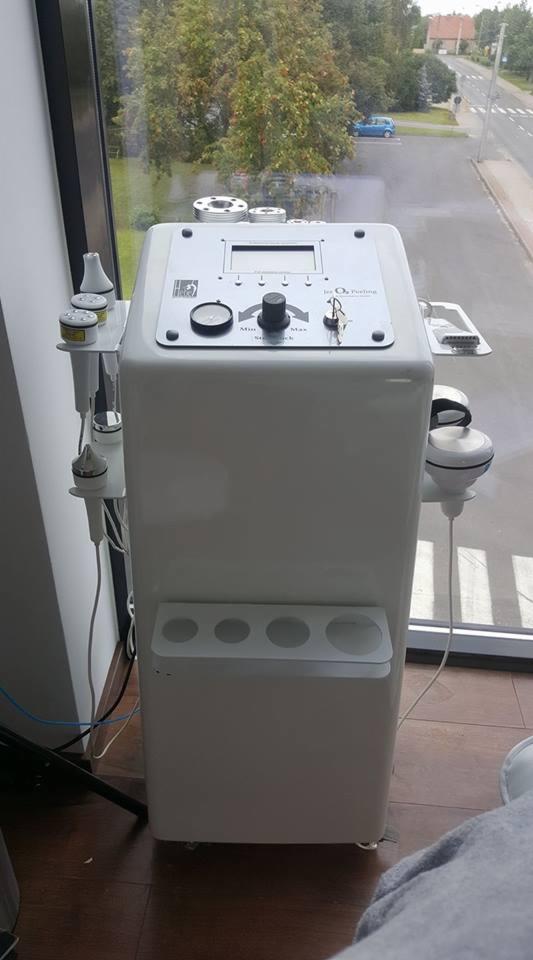 Profesjonalne urządzenie do zabiegów kosmetycznych, z różnymi końcówkami i wyświetlaczem, ustawione w gabinecie z widokiem na ulicę.