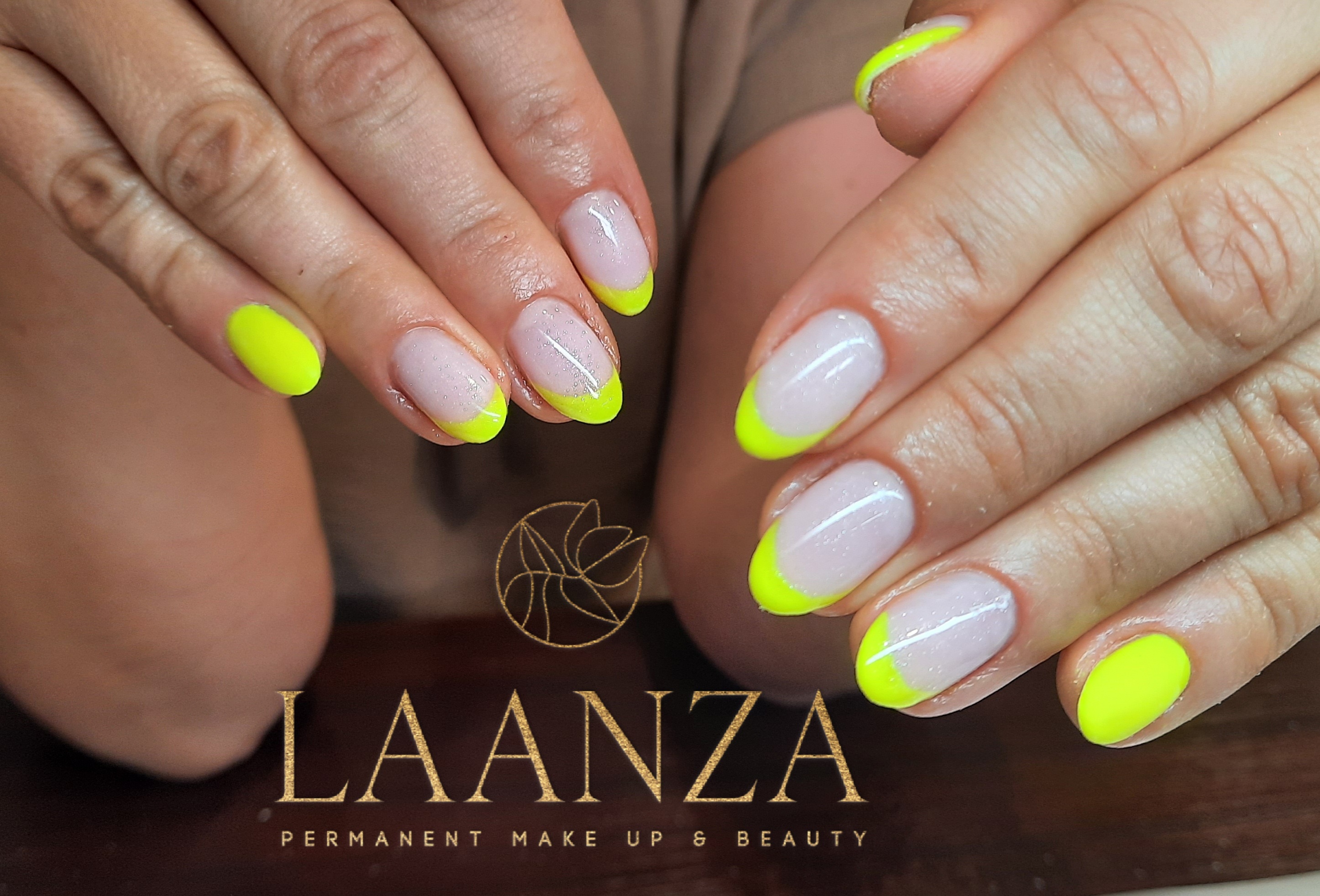 Zbliżenie na dłonie z owalnymi paznokciami, wykończonymi neonowo-żółtym french manicure, na tle logo salonu kosmetycznego.