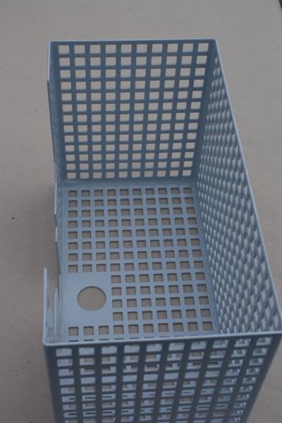 Szara, spawana konstrukcja z siatki z kwadratowymi oczkami i okrągłym otworem na dnie, widziana z góry pod kątem.