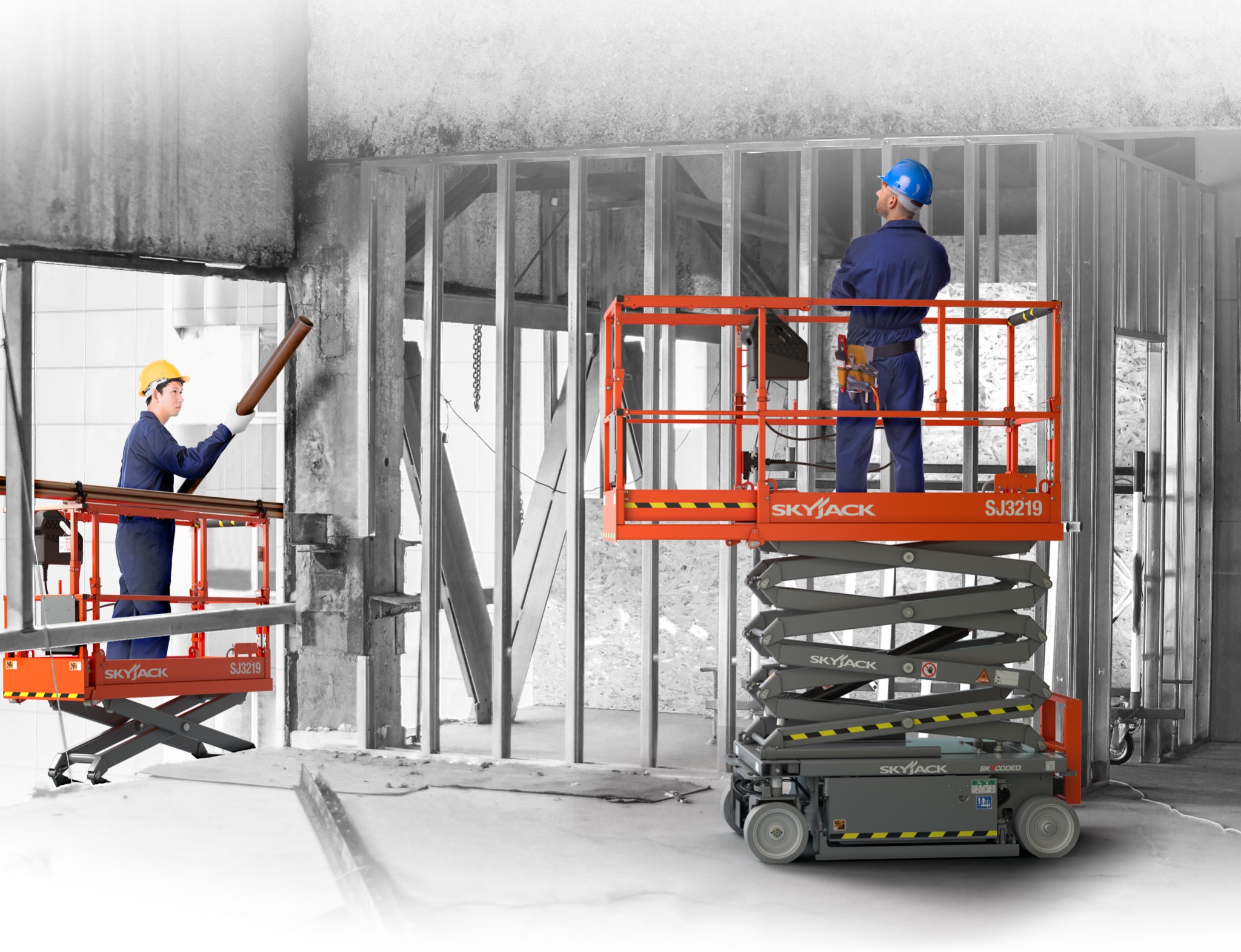 Dwóch pracowników budowlanych na pomarańczowych podnośnikach koszowych Skyjack SJ3219, jeden z rurą, drugi z założonymi rękami, w surowym wnętrzu budynku w trakcie budowy, z widocznymi metalowymi...