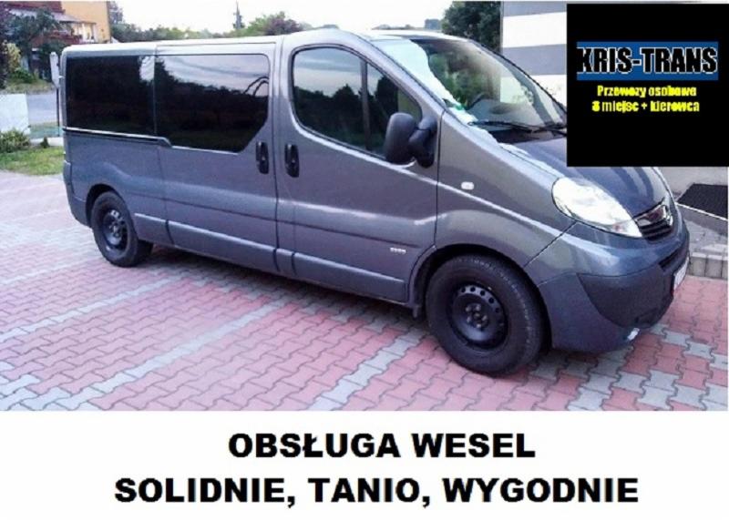 Szary bus z przyciemnianymi szybami, zaparkowany na chodniku z kostki, z naklejką reklamową 'Obsługa Wesel. Solidnie, Tanio, Wygodnie' i logo 'KRIS-TRANS' w prawym górnym rogu.