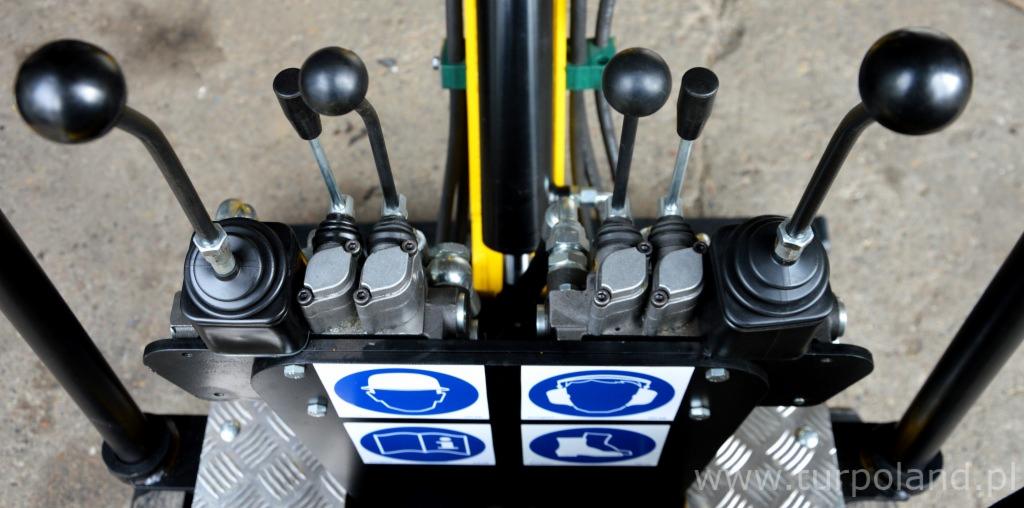 Panel sterowania z czterema dźwigniami i piktogramami BHP na metalowej platformie roboczej.