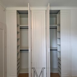 TOTAL RENOVATIONS SPÓŁKA Z OGRANICZONĄ ODPOWIEDZIALNOŚCIĄ - Biała szafa wnękowa z otwartymi drzwiami, widoczne półki i szuflady, drewniana podłoga, minimalistyczny design, subtelne oświetlenie.