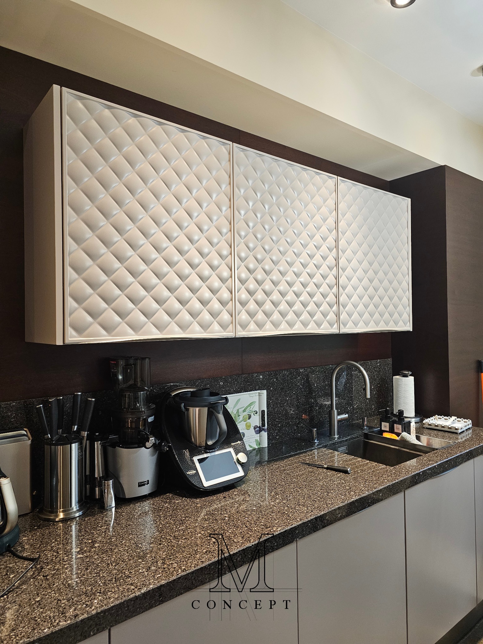 Kuchenna zabudowa: frezowane fronty MDF w romby, granitowy blat i okładzina. Nowoczesny sprzęt AGD, minimalistyczne szare szafki dolne. Elegancka aranżacja.