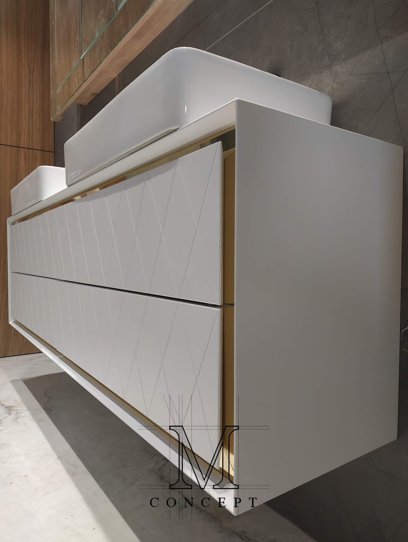 Biała szafka łazienkowa z umywalką nablatową, fronty z geometrycznym wzorem rombów, złote akcenty, nowoczesny design. Widok z boku, marmurowe tło.