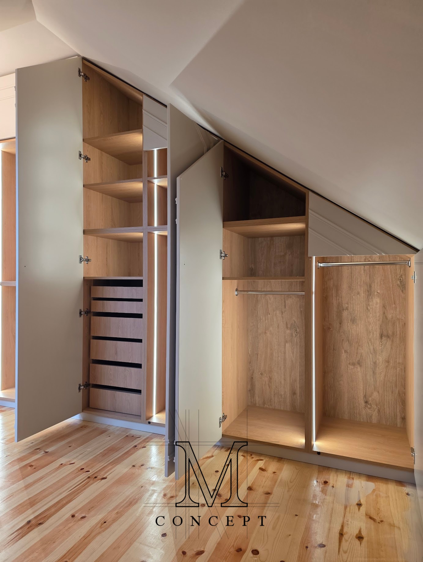 Szafa na poddaszu z MDF w półmacie, oświetlona LED. Widoczne półki, szuflady i drążki na ubrania. Uwagę zwraca dopasowanie do skosu dachu i drewniana podłoga.