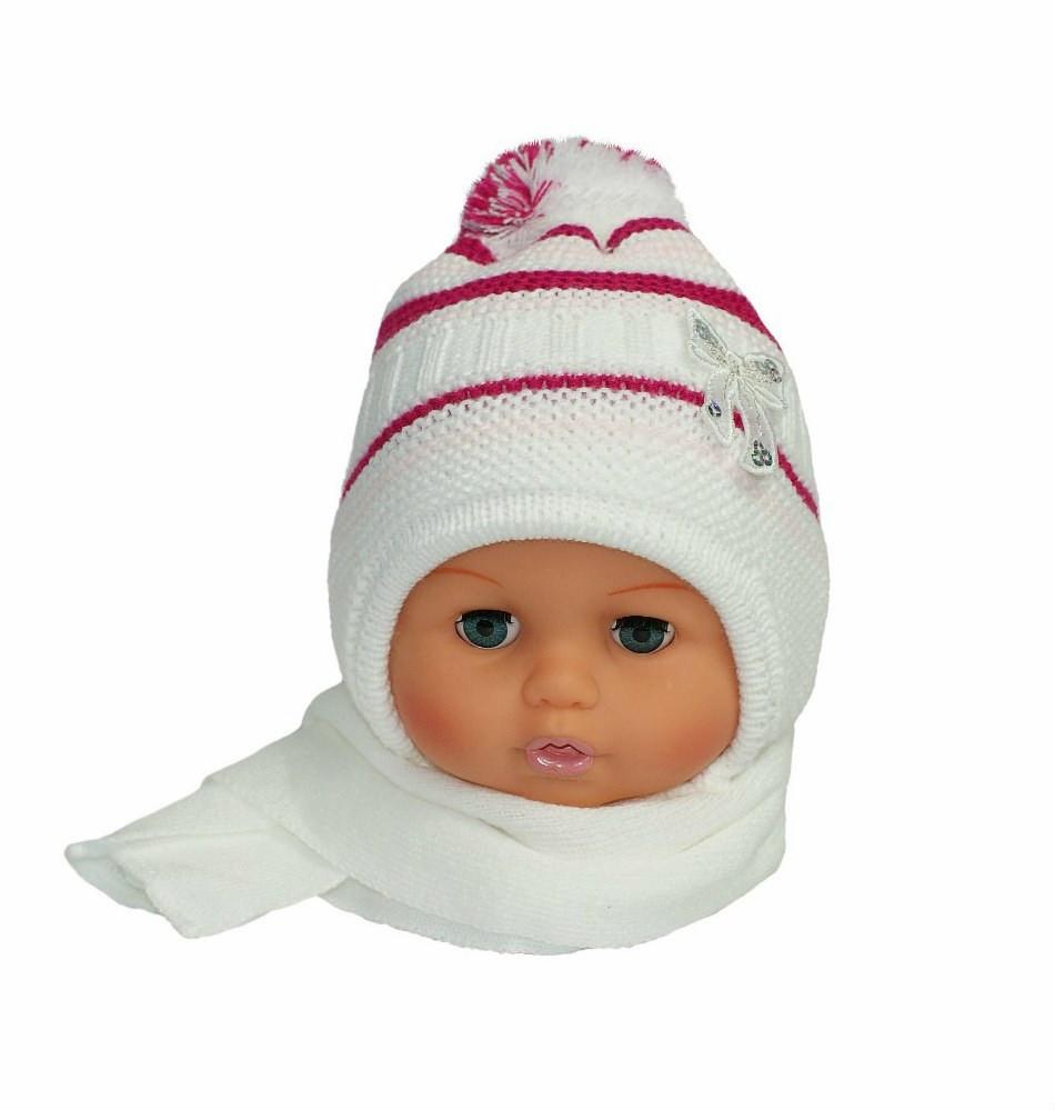 Manekin z niebieskimi oczami prezentuje białą, dzierganą czapkę z różowymi paskami i pomponem oraz biały szalik.